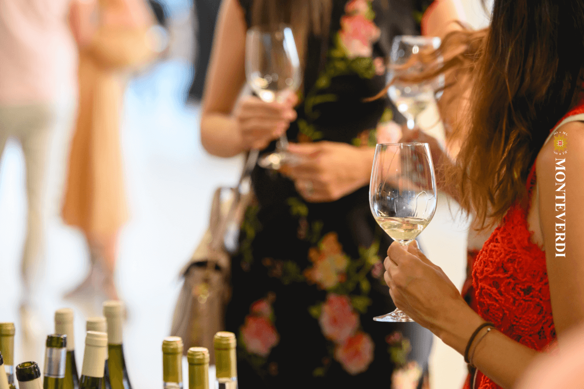 persone che stanno degustando calici di vino ad una fiera e conversano.